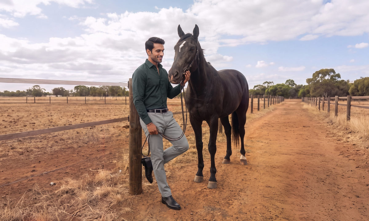 Man in a dark green Derby shirt with a black horse beside a ranch fence